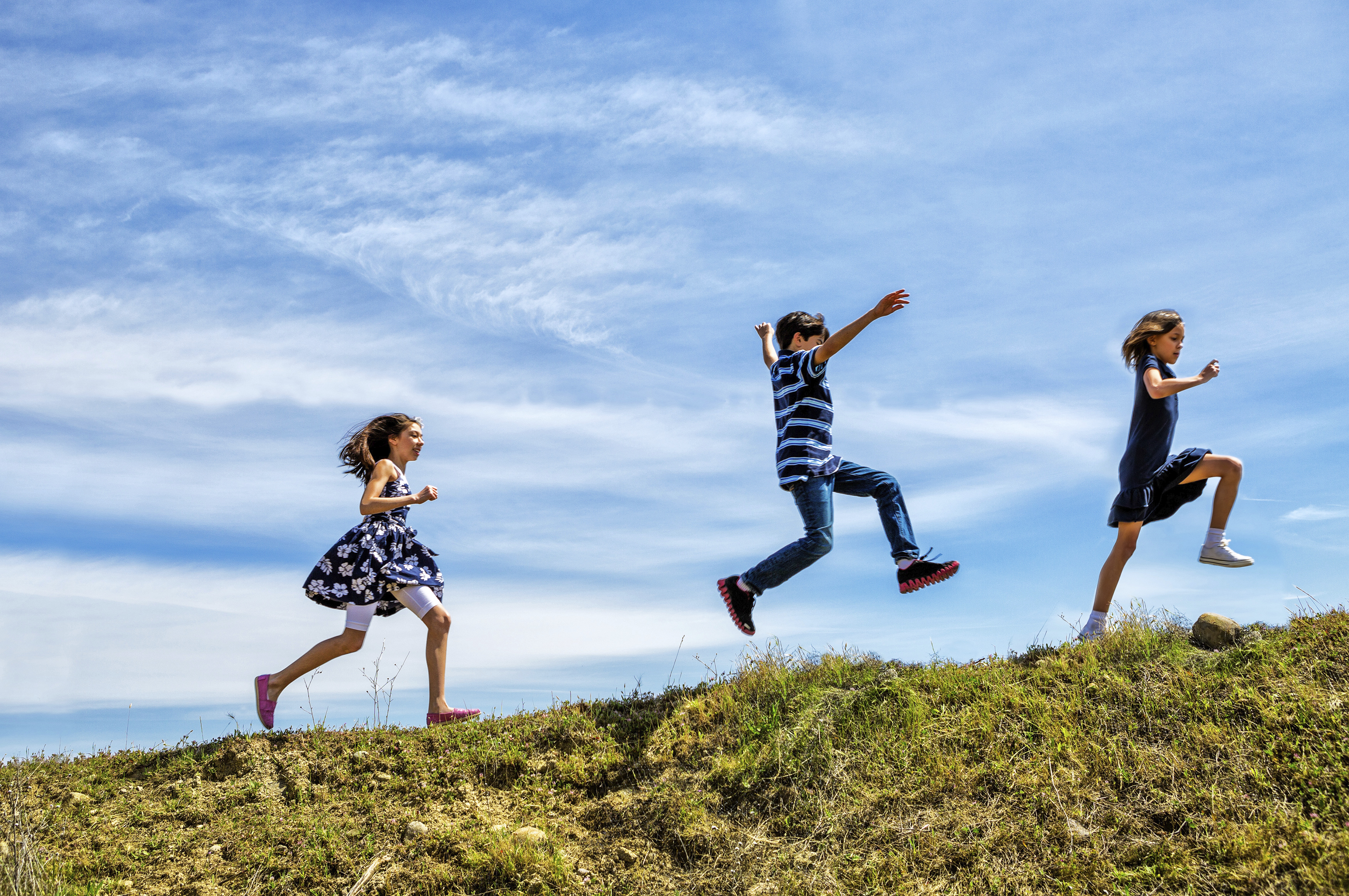 Children skipping and jumping up a hill.